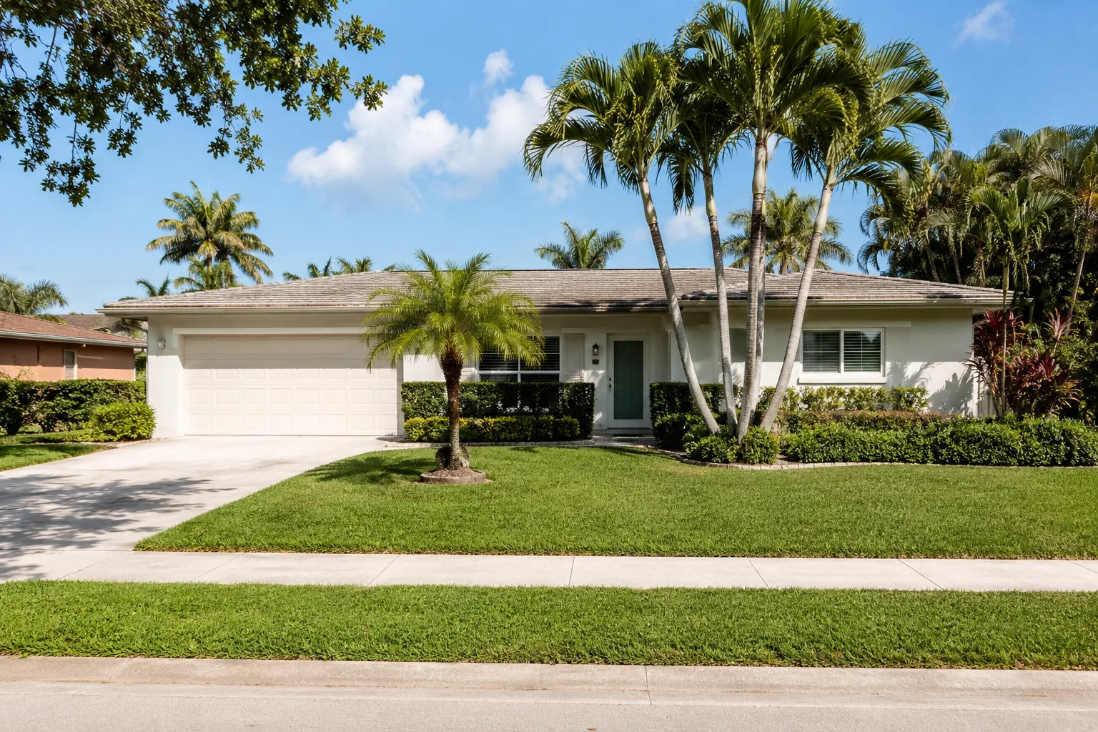 Exterior of the 1969 Vero Beach single-story home with palm trees and manicured lawn