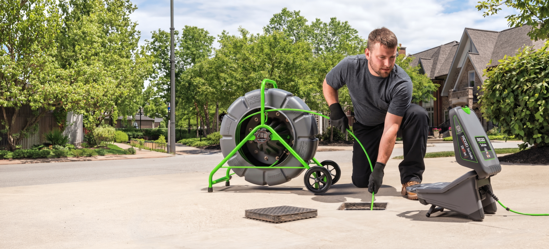 Technician deploying a push-camera reel to inspect a stormwater catch basin in a residential street.