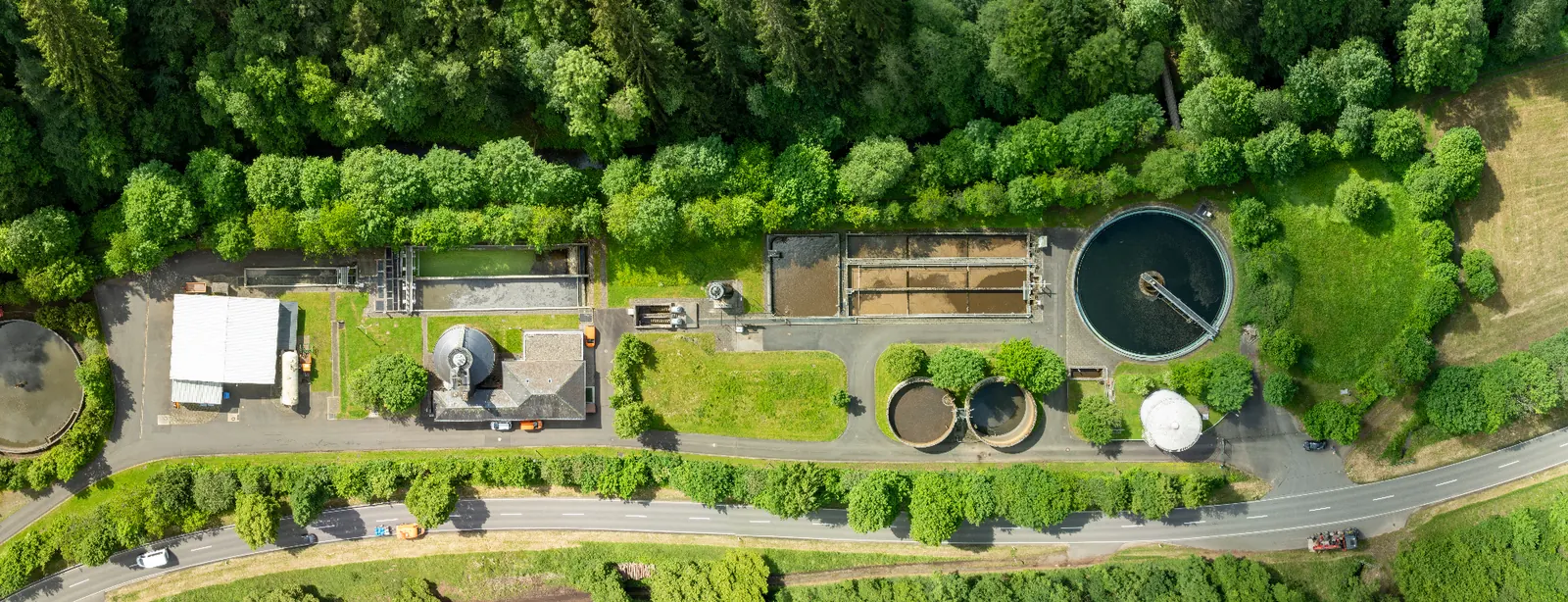 Aerial view of a small wastewater treatment plant surrounded by trees.
